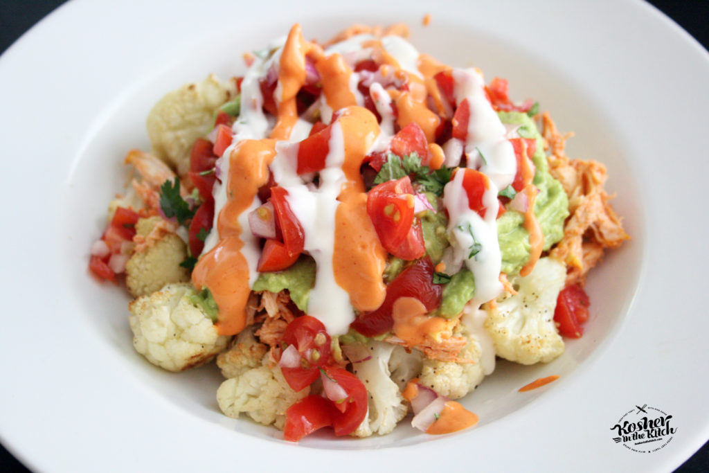 Cauliflower Nachos with Shredded Chicken, Guacamole and Pico De Gallo topped with Cilantro Lime Sauce and Creamy Hot Sauce