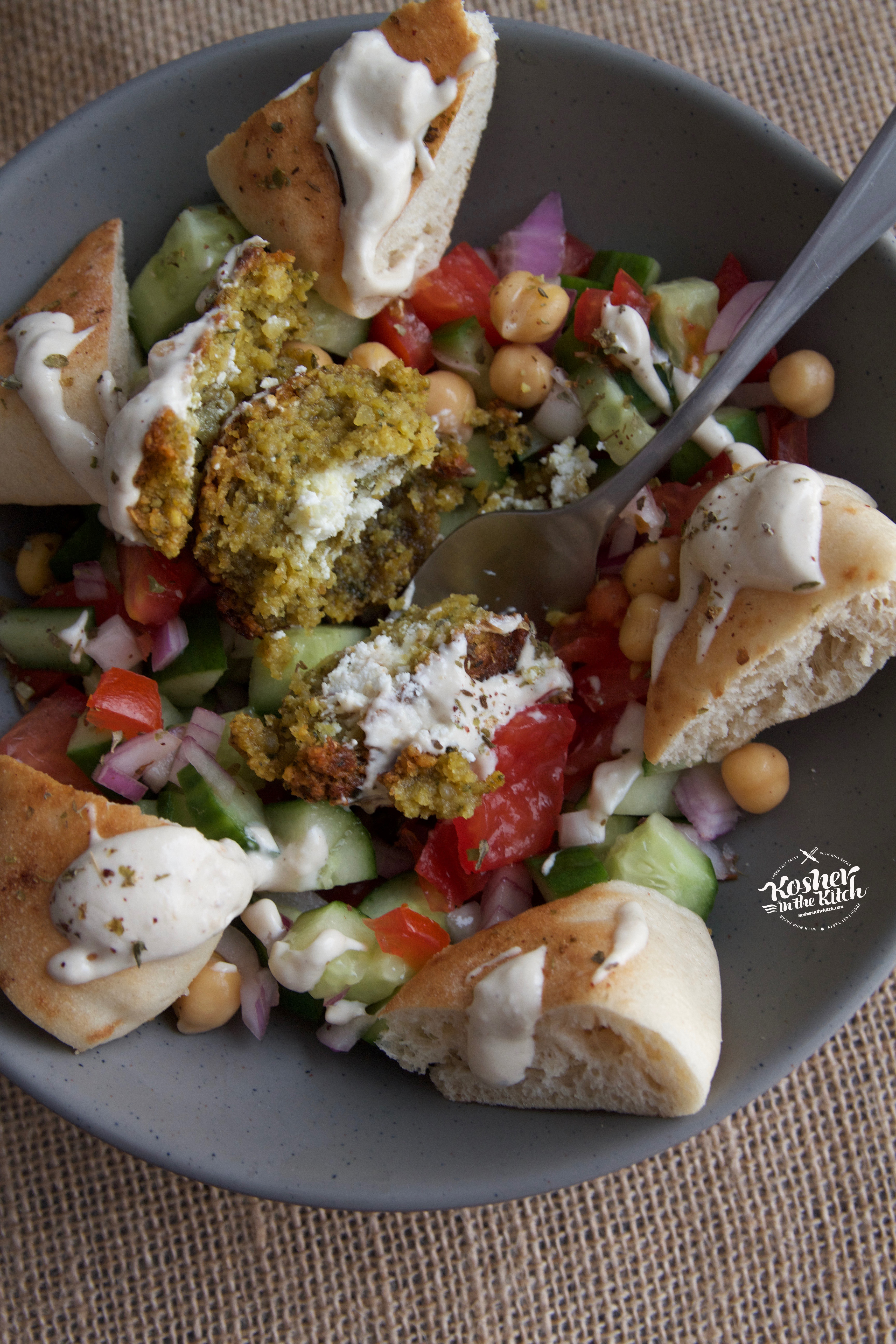 Falafel balls stuffed with goat cheese served over Israeli salad